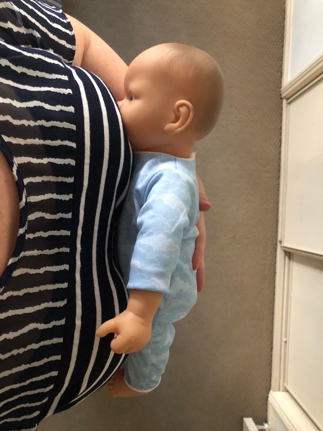 Baby doll demonstrating breastfeeding with good positioning, tummy facing in towards mum - Arlie Hastings Lactation Consultant - Breastfeed support with home visits in Gold Coast, Tamborine, Logan and Redlands areas.