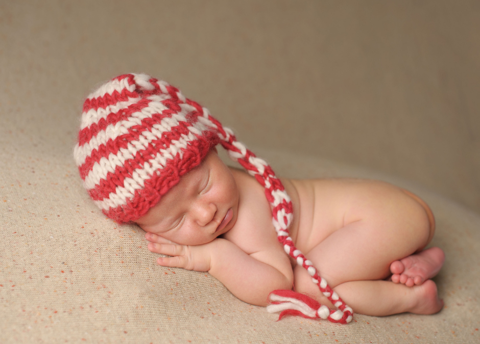 Newborn baby sleeping with a knitted stripey night cap on their head - Arlie Hastings Lactation Consultant. Breastfeeding support home visits in Gold Coast, Tamborine, Logan and Redlands. Telehealth video chat consultations.