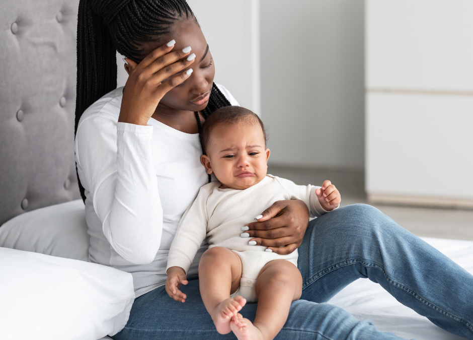 mother sitting on a bed looking upset with baby on her lap - Arlie Hastings Lactation Consultant. Breastfeeding support home visits in Gold Coast, Tamborine, Logan and Redlands. Telehealth video chat consultations.